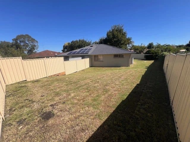Back yard mown short beside a house with solar panels
