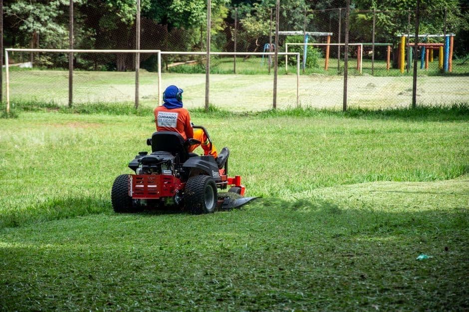 Worker on a ride-on mower cutting a large grass area